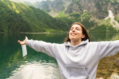 Kapatma sona erdi. Mutlu kadın tıbbi maskeyi çıkar, kadın gülen suratından koruyucu maskeyi çıkar. Güvendeyiz. Coronavirus bitti. Karantina kavramı bitti.