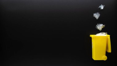 Plastik sıralama geri dönüşümü. Çöp konteynırı çöp atmak ve çevreyi korumak için. Siyah arkaplandaki plastik çöpleri geri dönüştürmek için sarı çöp kutusu. Düz yatıyordu.