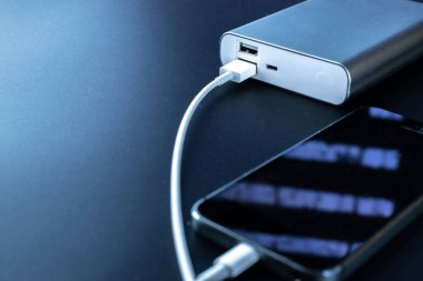 Telefon güç bankası. Cep telefonu ya da akıllı telefon bataryası beyaz USB kabloyla taşınabilir güç bankasından şarj oluyor. Mobil aygıtlar için dış pil.