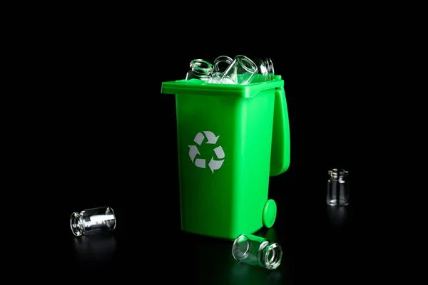 Una specie di vetro spazzatura. Contenitore per lo smaltimento dei rifiuti di immondizia e salvare l'ambiente. pattumiera verde per riciclare il vetro può cestino isolato su sfondo nero. — Foto Stock