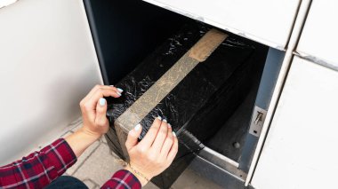 Otomatik dolap. Posta otomat terminalinde kadınların elinde bir paket kurye kutusu var. Kurye karton paketi paket dolabına koydu