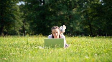 Bilgisayarlı öğrenci işleri, yaz parkında bilgisayar tableti. Kız arkadaş doğada çalışıyor. Teknoloji dışındaki insanlar. Elektronik aletler uzaklık öğrenme konsepti