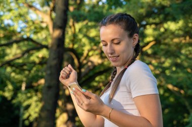 Gülümseyen kız telefonu. Parktaki güneşli bir günde elinde akıllı telefon tutan neşeli genç bir kız. Modern teknolojiler ve iletişim