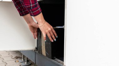 Otomatik dolap. Posta otomat terminalinde kadınların elinde bir paket kurye kutusu var. Kurye karton paketi paket dolabına koydu