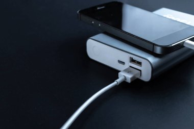 Şarj oluyor. Şarj cep telefonu ya da akıllı telefon bataryası için beyaz USB kablosu olan taşınabilir güç bankası. Elektronik aygıtlar konsepti
