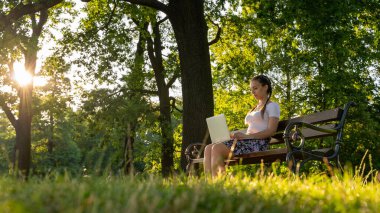Bilgisayar açık havada. Laptopta çalışan öğrenci kız, yaz parkında tablet. Çevrimiçi teknolojisi olan kadın ticareti. Elektronik aletler uzaklık öğrenme konsepti
