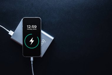 Telefon güç bankası. Cep telefonu ya da akıllı telefon bataryası beyaz USB kabloyla taşınabilir güç bankasından şarj oluyor. Kopyalama alanı olan mobil aygıtlar için dış pil