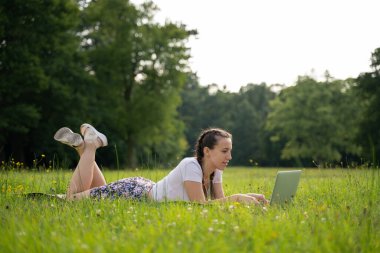 Öğrenci kız arkadaş tablet üzerinde çalışıyor, bilgisayar yaz parkında. Çevrimiçi kadın dışarıda. Laptop açık hava iş teknolojisi. Elektronik aletler uzaklık öğrenme konsepti