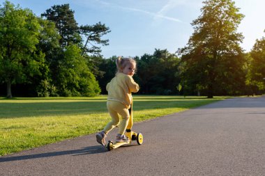 Scooter 'lı çocuk. Scooter süren bir kız. Sarı açık hava faaliyet parkı yolu