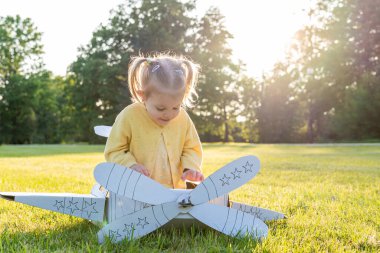 Uçak kostümü. Bebek hayal gücü uçuyor. Açık hava sarı çimen eğlencesi.