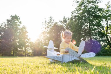 Küçük pilot. Uçak karton çocuk kostümü. Fantezi oyunu sarı çimen.