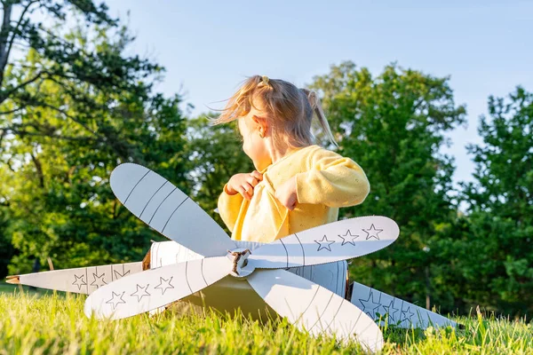 Oyun oynuyormuşsun gibi yap çocuk. Kız havacılık pilotu oyuncağı. Yaz eğlencesi açık hava kartonu