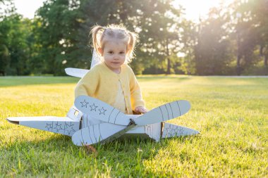 Oyun oynuyormuşsun gibi yap çocuk. Kız havacılık pilotu oyuncağı. Yaz eğlencesi açık hava kartonu