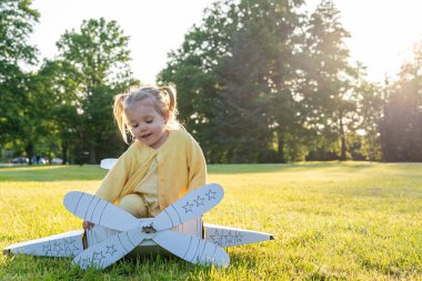 Karton uçak. Çocuk pilot dışarıda oynuyor. Bebek kostümlü kız tarlası sarısı