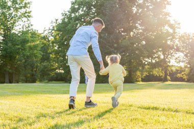 Baba kızı. Baba gün batımında küçük kızıyla koşuyor.