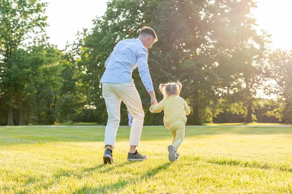 Baba kızı. Baba gün batımında küçük kızıyla koşuyor.