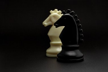 Satranç. Siyah arka plan üzerine siyah ve beyaz şövalyeler. Satranç figürleri kümesi. Satranç atlar.
