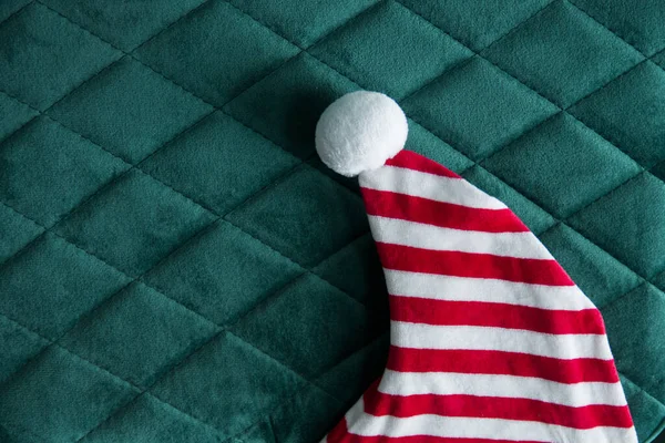 Beyaz ponponlu kırmızı ve beyaz çizgili elf şapkası Noel Baba 'nın yardımcısı, süslü elbise, çocuklar için kostüm. Boşluğu olan yeşil arkaplan