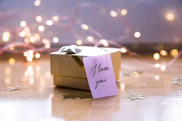  Sevgililer günü için seni seviyorum yazılı küçük altın bir hediye kutusu. Noel ışıkları bokeh odaklanmamış arkaplan. 
