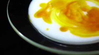 Kozmetik süte karoten damlası ekliyorum. Beyaz süt ve turuncu beta karoten solüsyonunu ahşap spatulayla karıştırıyorum. Kapatın. Döndürme. Yüz ve vücut için cilt bakımı ürünü. Güzellik konsepti.