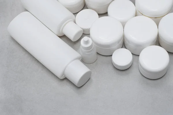 Model. Jel, losyon, krem için boş şişe ve kavanoz. Etiketsiz cilt ürünleri için beyaz plastik kaplar.