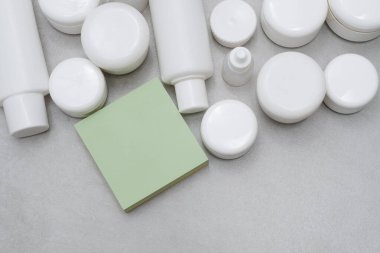 Model-up. Boş yapışkan yapışkan notlar. Boş beyaz plastik şişeler ve kavanozlar. Etiketsiz ürünler. Markasız güzellik ürünü paketi. Reklam veya tanıtım metinleri için yer var..