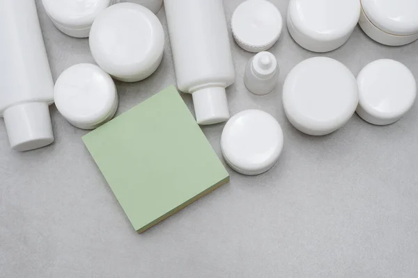 Model-up. Boş yapışkan yapışkan notlar. Boş beyaz plastik şişeler ve kavanozlar. Etiketsiz ürünler. Markasız güzellik ürünü paketi. Reklam veya tanıtım metinleri için yer var..