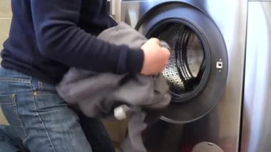 İşçi çamaşır makinesini çamaşır makinesine yükler. İş kıyafetlerini yıkıyor. Sıradan insanların sahnelenmemiş videosu