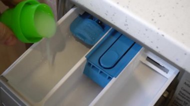 Çamaşır makinesinin en üst görüntüsü. Çamaşır makinesine el tozu döker..