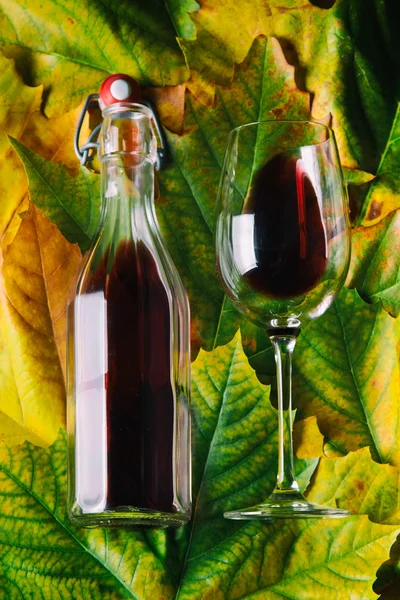 Vinho tinto em folhas de outono fundo — Fotografia de Stock