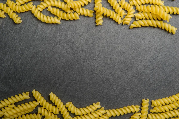 Spiral pasta på en svart sten bakgrund. Utsikt uppifrån. Horisontellt foto — Stockfoto