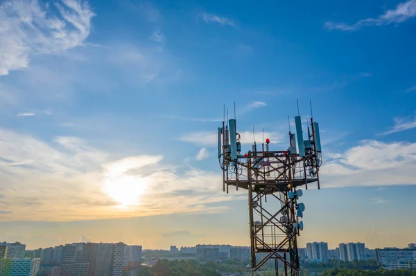 Silhouette torre di comunicazione operatori di telefonia mobile antenna sullo sfondo blocchi della città e il cielo blu sera. — Foto Stock