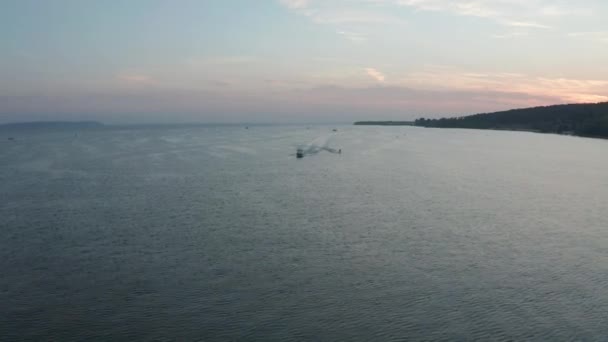 Veduta aerea di una barca a motore ad alta velocità che tira uno sciatore d'acqua. ora di sera dopo il tramonto. — Video Stock