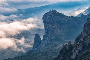 Kayalık dağların, sisli ve bulutlu vadinin görkemli manzarası. Kremalı sis dağ vadisini gün batımıyla kapladı. Kırım Dağları üzerinde puslu gün batımı. Konum Ai-Petri, Kırım.