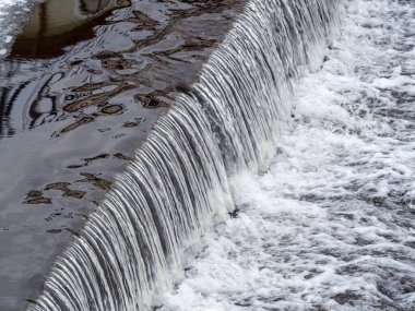 Sakin bir nehirde küçük düz bir şelale. Su arkaplanı