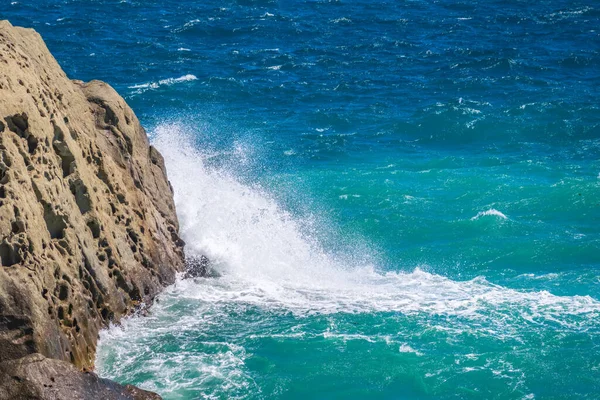 Sea water beats against rocks. Sea waves of dark water beat against the coastal rocks. An infinite number of splashes, drops of water and white foam are scattered.