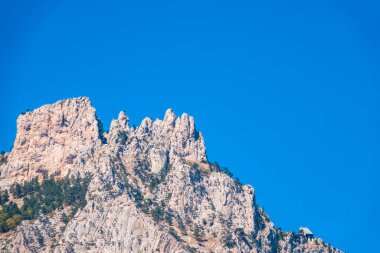 Ormanlık yamaçlı yüksek dağlar ve mavi gökyüzü arka planında zirveler. Kırım Dağları aydınlık bir günde. Konum Ai-Petri, Kırım.