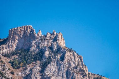 Güneşli bir günde kayalık dağların görkemli manzarası yayılır. Kırım Dağları 'nın üzerinde açık bir gökyüzü. Konum Ai-Petri, Kırım.