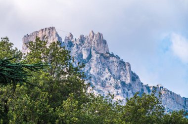 Bulutlu arka planda ormanla kaplı yeşil dağ. Dağlarda yeşil odun.