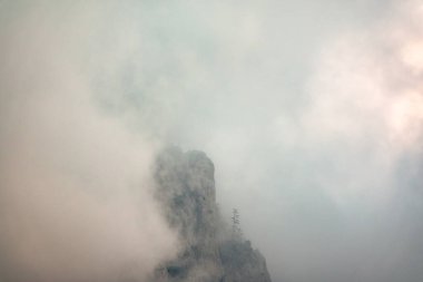 Yoğun bulutların ve sislerin arasına gizlenmiş kayalık yamaçları olan yüksek bir dağ. Bulutlu bir günde dağlarda yoğun sis var. Dramatik bulutlu gökyüzü