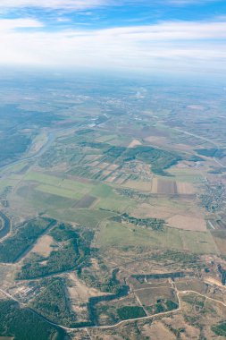 Yeşil zeminin üstündeki uçak penceresinden hava görüntüsü. Güneşin doğuşunda güzel bulutların olduğu uçak penceresinden bak. Dünya ve gökyüzü bir uçağın penceresinden görüldüğü gibi.