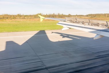 Uçak kanadının görüntüsü, iniş sırasında uçağın gölgesi, uçak penceresinden görüldü. Dünya ve gökyüzü bir uçağın penceresinden görüldüğü gibi.