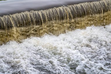 Sakin bir nehirde küçük düz bir şelale. Su arkaplanı