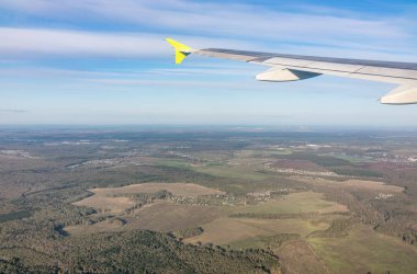 Moskova, Rusya 'ya iniş sırasında uçak kanadı, mavi gökyüzü ve kara manzarası. Uçak penceresi manzaralı. Dünya ve gökyüzü bir uçağın penceresinden görüldüğü gibi.