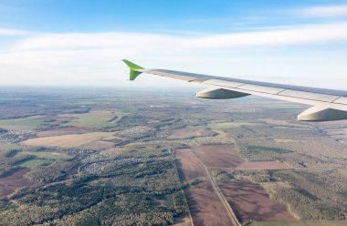 Moskova, Rusya 'ya iniş sırasında uçak kanadı, mavi gökyüzü ve kara manzarası. Uçak penceresi manzaralı. Dünya ve gökyüzü bir uçağın penceresinden görüldüğü gibi.