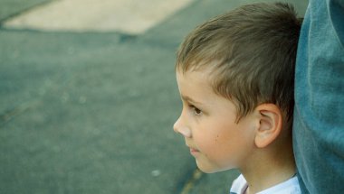 the child stands next to dad and looks into the distance  