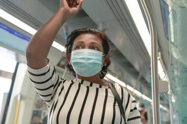 Trenin içinde maske takan bir kadın. Salgın sırasında yeni normal seyir.