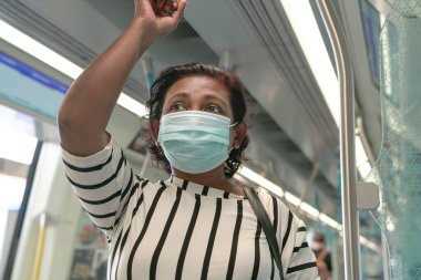 Woman commuter wearing face mask inside train. Travel new normal during pandemic. clipart