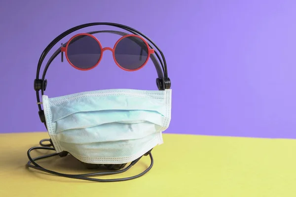 Head phones wrapped with face mask and sun glasses. Wear a mask concept.