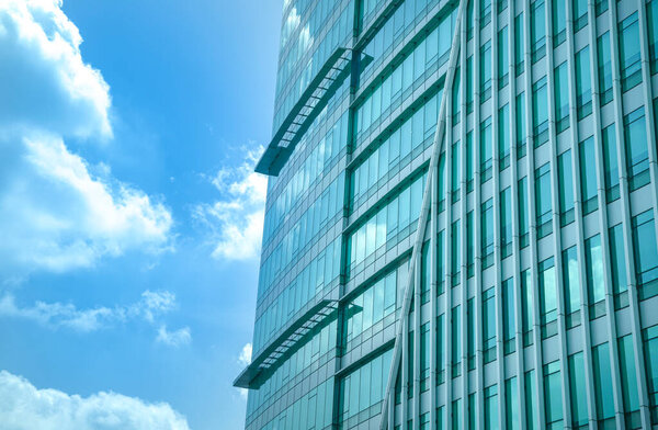Modern high rise office building with reflection of blue sky and clouds on windows